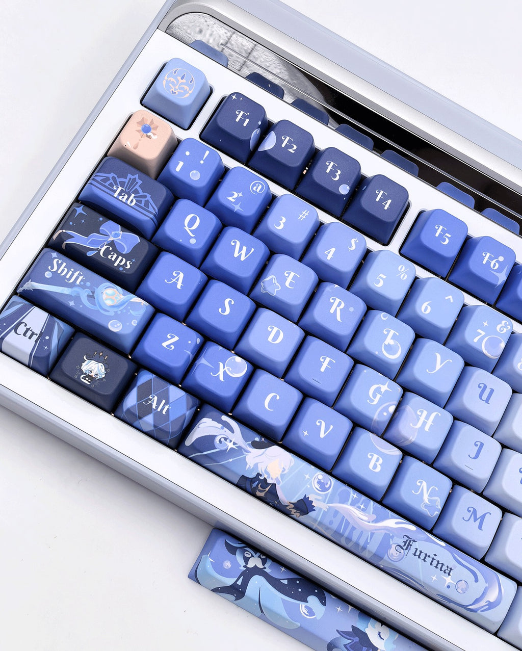 A close-up of a mechanical keyboard with Furina keycaps, featuring fantasy-themed illustrations and white lettering. A matching spacebar is placed below the keyboard on a clean white surface.